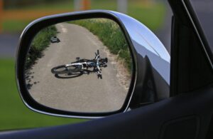 Bike on its side laying on the road seen from a car's side mirror